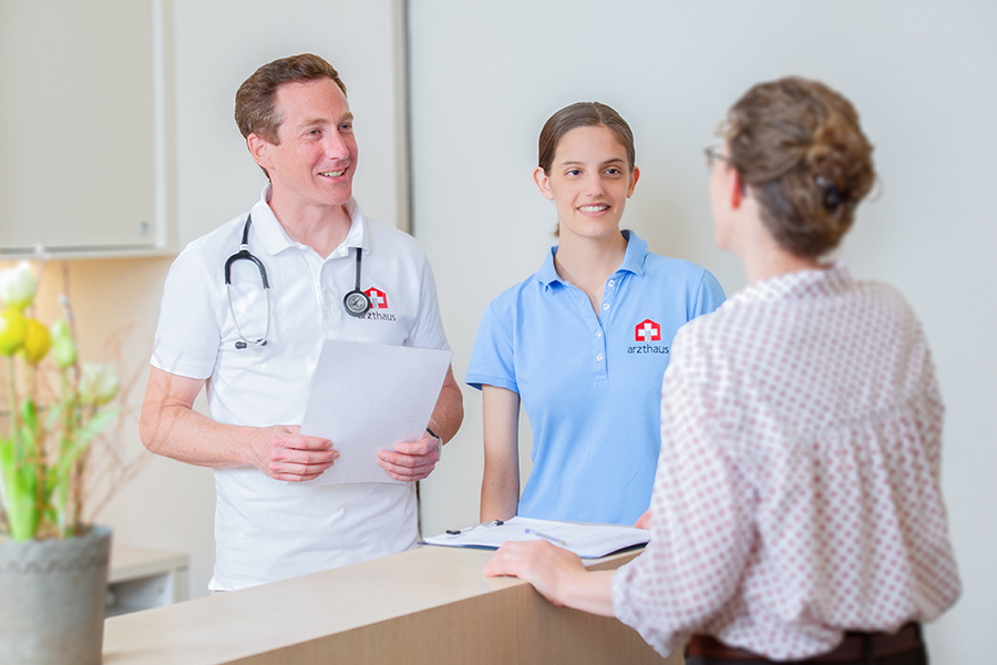 Patient greated by doctor and nurse at the reception desk