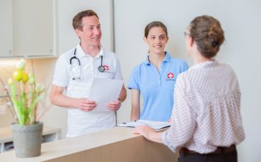 Doctor, nurse and patient talking at the reception desk of a clinic