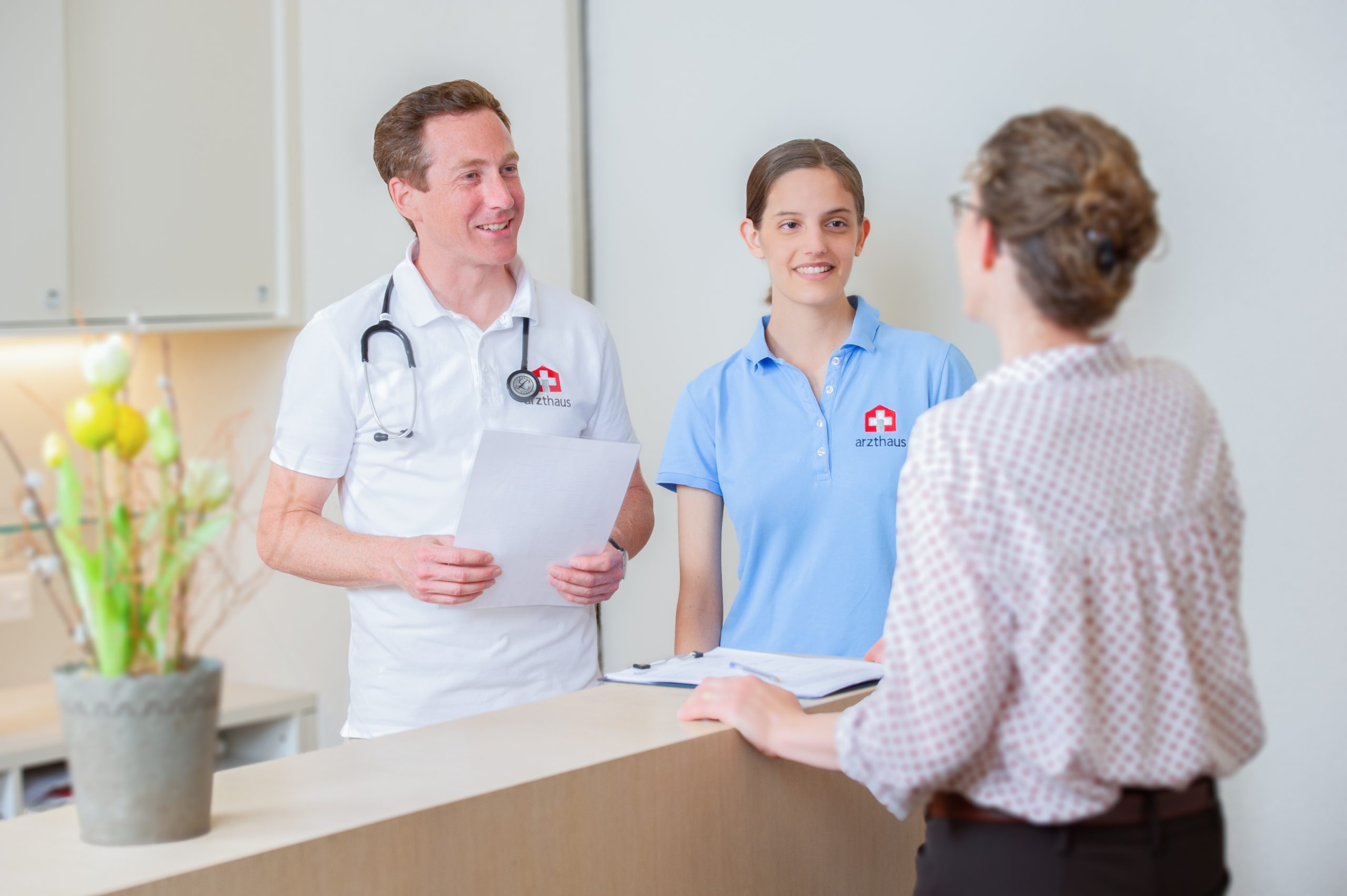 Doctor, nurse and patient talking at the reception desk of a clinic